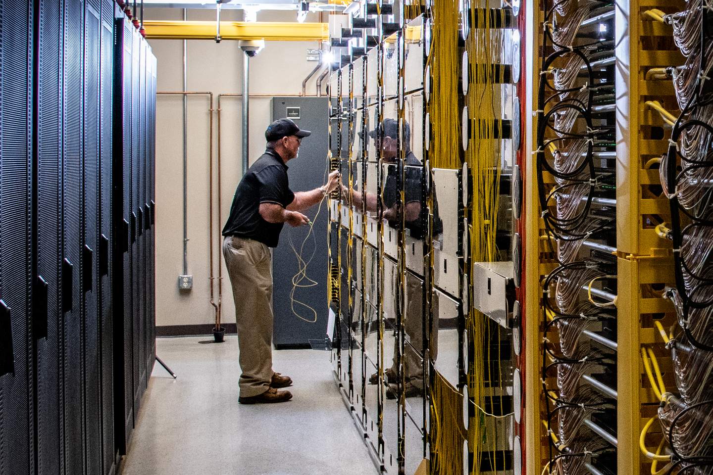 A technician installing fiber optic cabling between equipment racks at the NCTC data center in Lafayette, Tennessee